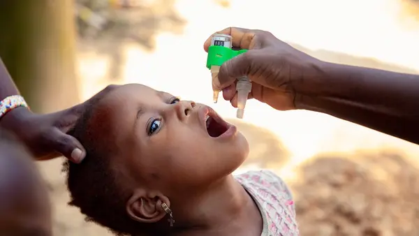 A child receives polio drops from UNICEF-supported vaccinator in DR Congo.