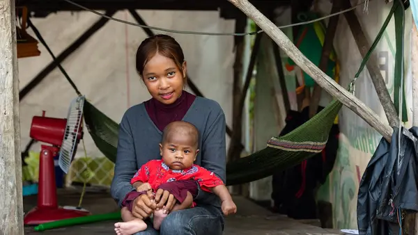 Korng, 14, holds her 3-month-old brother Kung outside their home in Ta Ley, a village in Phnom Penh's impoverished Dang Kao district.