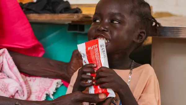 A severely malnourished child in Sudan holds a packet of ready-to-use therapeutic food that UNICEF supplies for treatment.