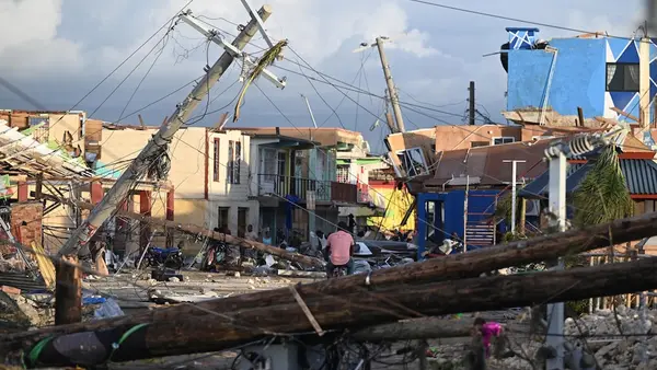 A man rides a bike through a badly damaged neighborhood in Black River, Jamaica after Hurricane Melissa.