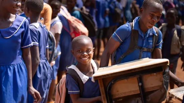 Students carry new desks from the K.I.N.D. Fund into their school in Malawi.