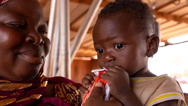 A mother feeds her 11-month-old child a packet of ready-to-use therapeutic food supplied by UNICEF.