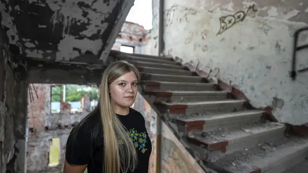 Sofiia, 17, stands in the stairwell of a ruined building in Kharkiv, Ukraine.