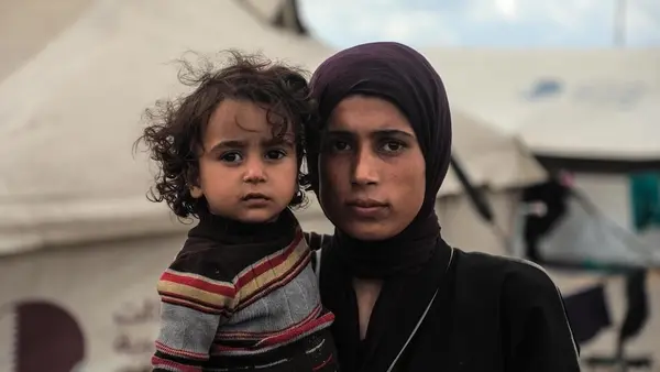 A mother holds one of her children in a displacement camp in Gaza in November 2025.