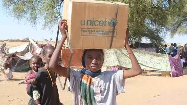 A teenage girl in Tawila, Sudan, holds a box containing emergency supplies from UNICEF.