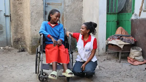 Kibra, 15, sits in her wheelchair next to Mikal, a social worker supported by UNICEF, outside Kibra's home in Tigray, Ethiopia.
