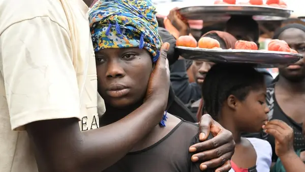A young girl is held close by a caregiver during a community awareness-raising event about female genital mutilation (FGM) in Conakry, Guinea.