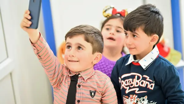 Preschool students share a cell phone in Lori, Armenia.