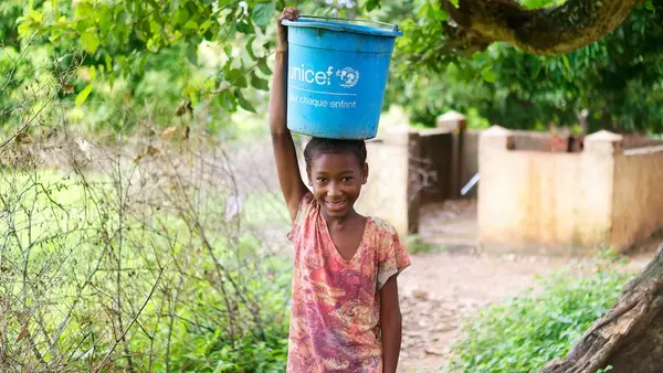 A young girl carrying a bucket of water donated by UNICEF on her head in Madagascar. 