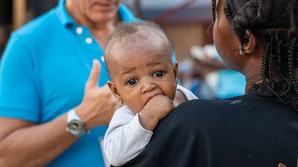 In Haiti following Hurricane Melissa, a UNICEF representative speaks with a mother holding a small child about the needs of impacted families and communities.