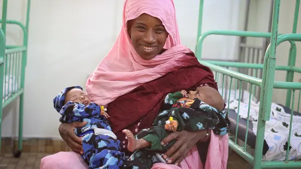 A mother holds her newborn twins at a health clinic that runs on solar power thanks to UNICEF.