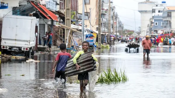 Children in Madagascar walk through flooded streets carrying scrap metal in wake of Cyclone Gezani.
