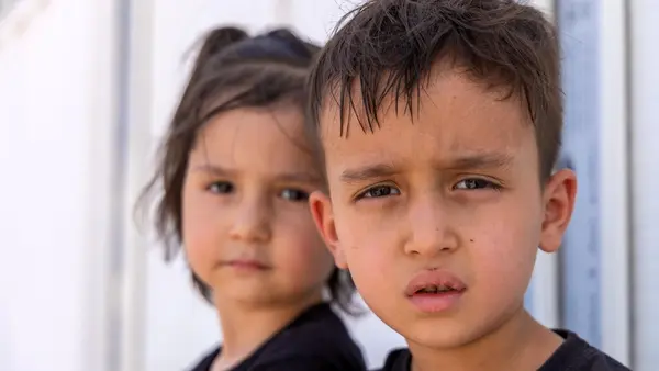 Amir Ali, 5, and Baran, 3, sit next to their family’s belongings in the reception area at the Islam-Qala border crossing, just hours after returning to Afghanistan from Iran.