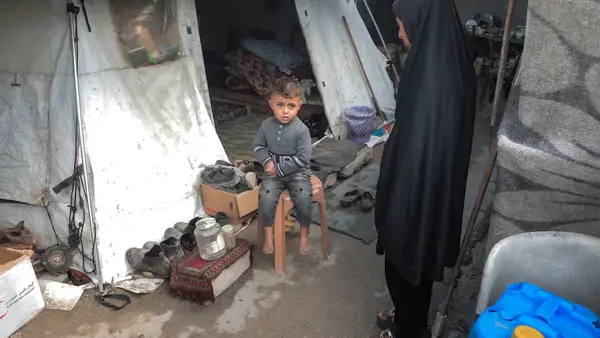 In Gaza, a small child sits by his mother outside their flooded tent.