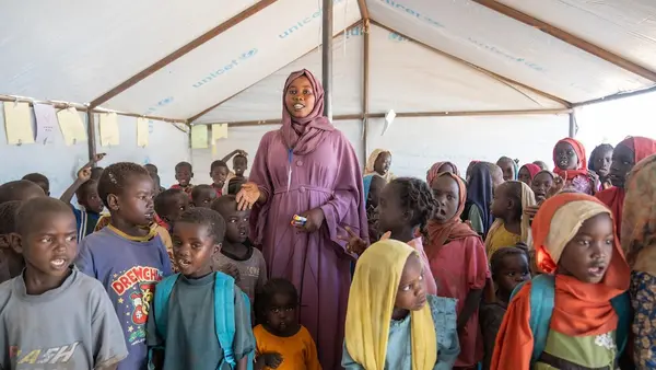 A volunteer stands inside a UNICEF safe learning space full of children in Tawila, North Darfur, Sudan.