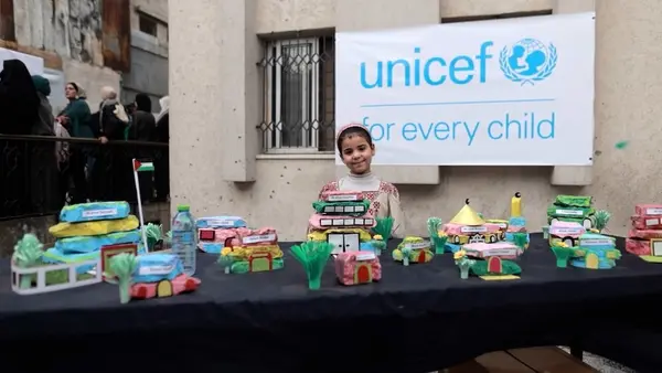 A child stands with children's models of houses, schools and hospitals they want to see built in Gaza.