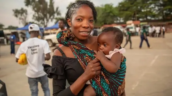 A mother in Zambia holds her child who has just received a malaria vaccination.