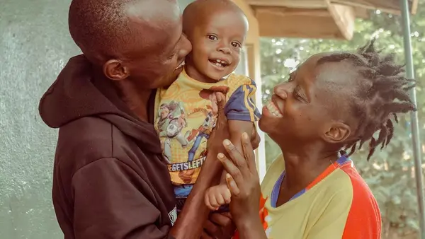 A boy and his parents in Sierra Leone celebrate the child's recovery from severe acute malnutrition.