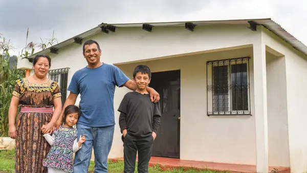 Family smiling together in front of a house