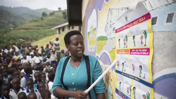 A woman shares information about Ebola with community members in Uganda.