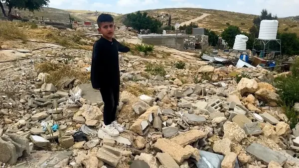 In the Hebron Hills, southern West Bank, a boy points to where his home stood before it was destroyed by Israeli settlers. 