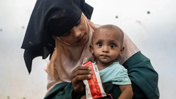 A Rohingya refugee mother feeds her child ready-to-use therapeutic food supplied by UNICEF to treat severe malnutrition.