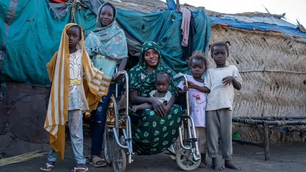 A mother sits in her wheelchair with her five children around her outside the family's home in rural Gedaref, Sudan.