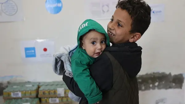 A boy holds his baby brother in a UNICEF ready-to-use complementary food distribution site in Gaza City. 