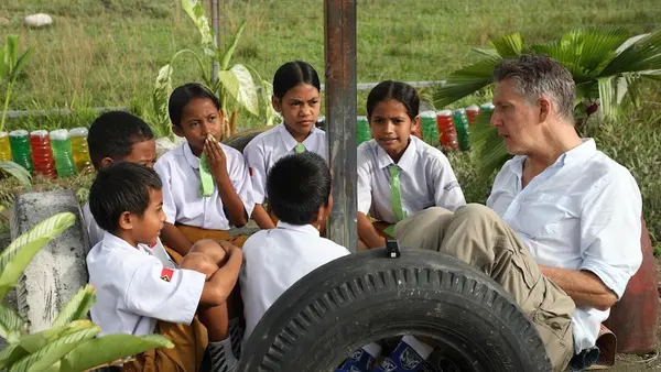 Schoolchildren in Timor-Leste talk with UNICEF spokesperson James Elder, far right. 