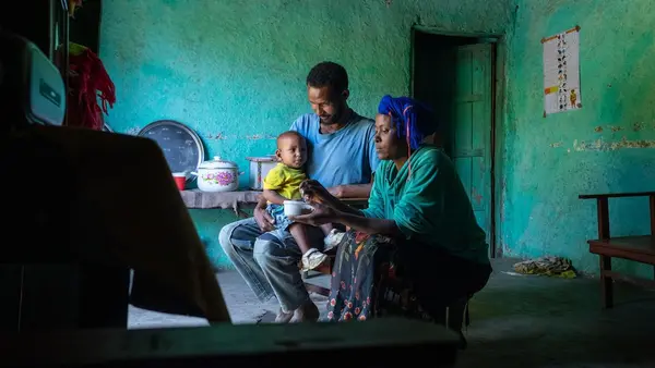 A mother and father at home in Ethiopia with their infant child.