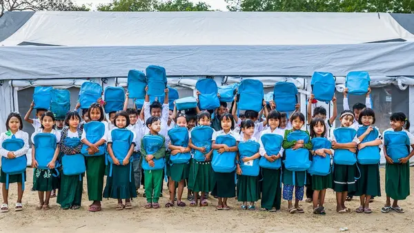 Children hold UNICEF backpacks outside a school tent at BEHS Pyitharyar in Pyawbwe Township, Mandalay Region, Myanmar.