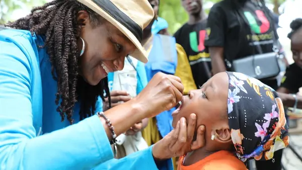 UNICEF's Representative in Cameroon smiles while giving the oral polio vaccine to a young child in the Far North region.