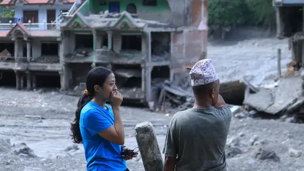 On Aug. 27, 2026, a UNICEF staffer talks to a community member in  Nuwakot District, Bagmati Province, Nepal, as homes and surrounding areas can be seen covered in mud. 
