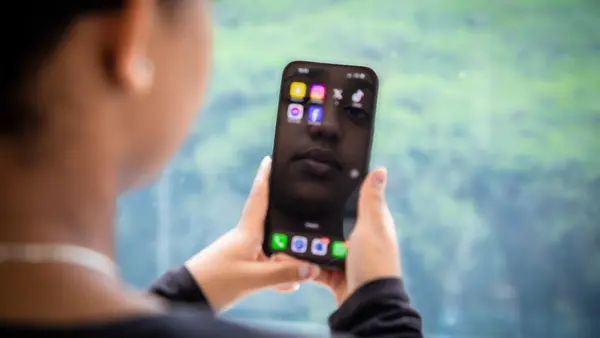 A child looks at her image reflected on a cellphone. 