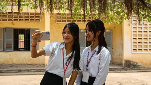 Two Grade 9 girls use social media on their phones outside their school in Battambang Province, Cambodia.  .