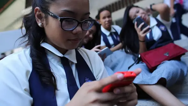 Schoolgirls look at their smartphones.