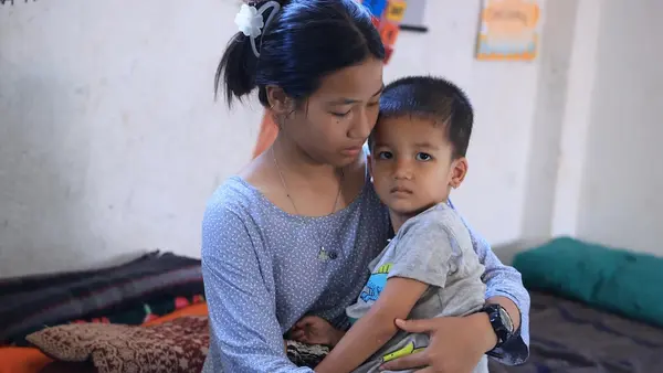 A 13-year-old girl holds her 3-year-old brother on her lap in Nepal.