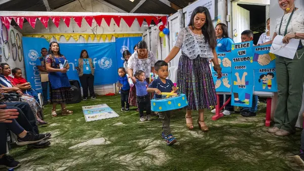 Children carry homemade instruments during an impromptu parade to welcome guests at a UNICEF-supported early childhood development center in Guatemala. 