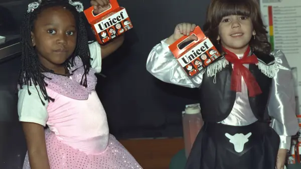 Two children in Halloween costumes hold their Trick or Treat for UNICEF boxes.