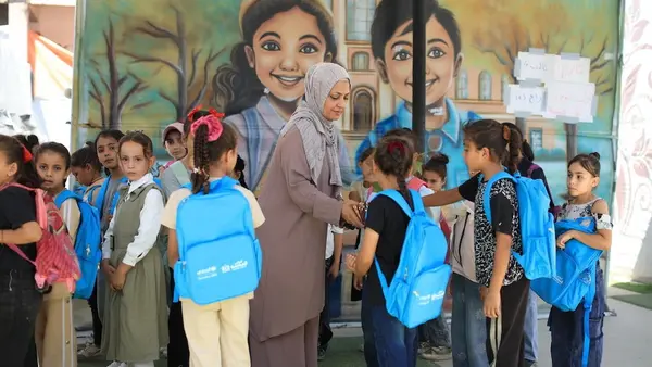 Children with UNICEF backpacks greet their new teacher on the first day of school in Gaza on Sept. 21, 2026.
