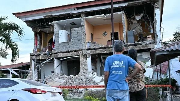 Man and woman look up at earthquake damaged home in Panama