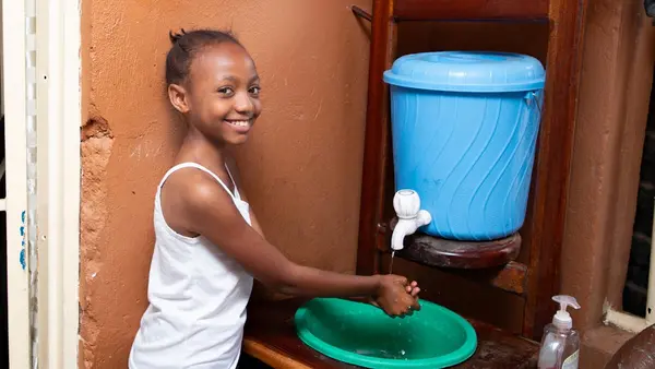 Ketsia, 10, washes her hands with soap and water at her home in Bunia, Democratic Republic of the Congo.