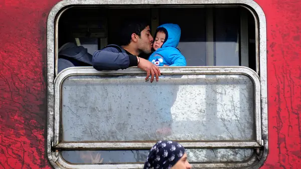 A father kisses his baby boy inside a train filled with refugees from Syria and Iraq travelling across Macedonia to the Serbian border, where they will continue their journey.