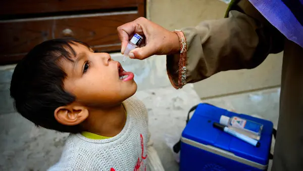 A 5-year-old boy receives the polio vaccine from Shumaila, a UNICEF-supported polio vaccinator in Lahore, Pakistan on January 11, 2021. 