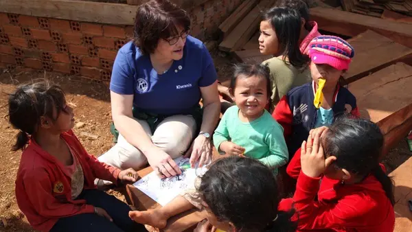 Kiwanis International President Sue Petrisin teaches children to draw on a field visit in Cambodia.