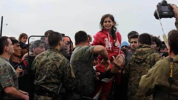 A child refugee being lifted above the crowd at the Greek border after escaping via the Balkan Route