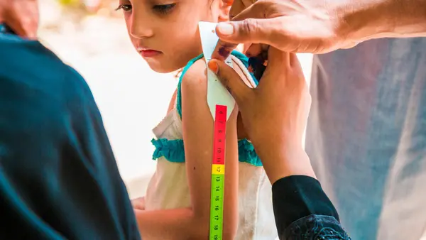 A child has her upper arm measured to screen for malnutrition as part of a door-to-door immunization campaign in Yemen in October 2017.