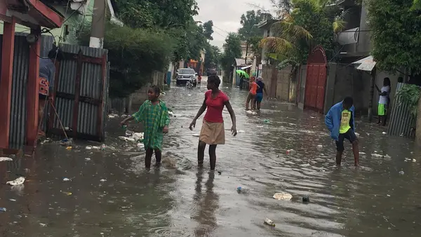 On 7 September 2017 in Haiti, children and women wade through a street in Hinche as Hurricane Irma approaches.