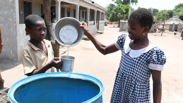 Two young children drinking safe water in the village of Kotouba, in northwest Côte d'Ivoire.