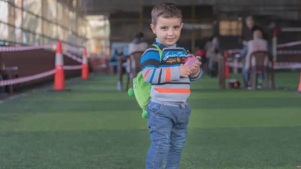 Syrian refugee child in Lebanon holds his mother's new LOUISE common card, which will allow the family to access all the cash-based aid programs for which they are eligible.